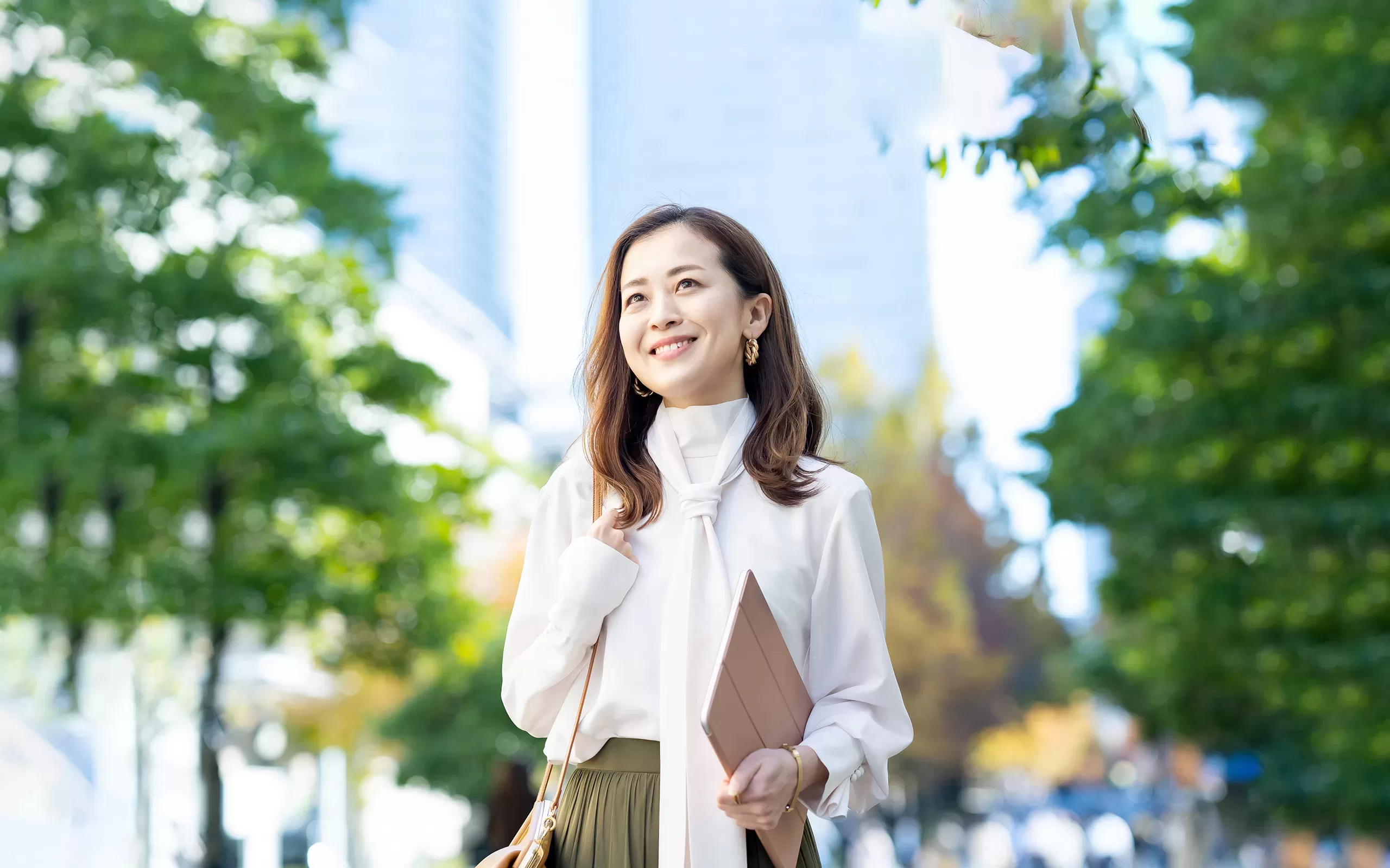Femme japonaise souriante dehors avec une tablette de la main et bien habillée